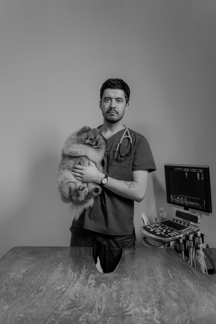 Vet in scrubs carrying a small dog